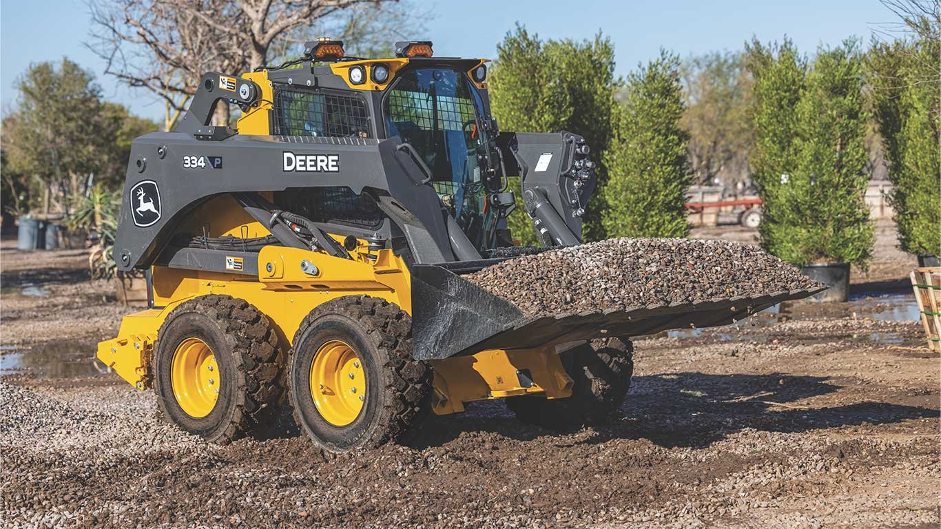 The John Deere 334 P-Tier scooping gravel in a bucked on the jobsite