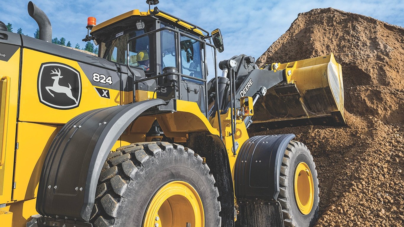 824 X-Tier Wheel Loader scooping dirt into a bucket on the jobsite